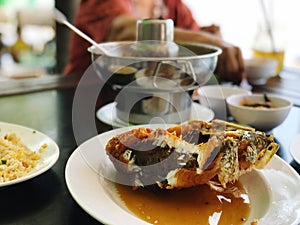 Fried fish with spicy soup on the table in the restaurant.