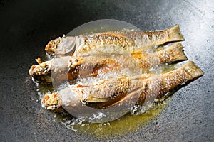 Fried fish. Three fishes frying in hot oil in pan or skillet