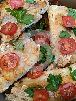 Fried fish with tomatoes, parsley leaves and spices