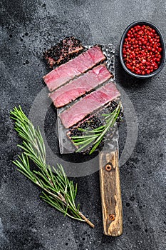 Fried fish tuna steak slices on a meat cleaver. Black background. Top view