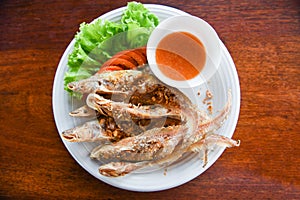 Fried fish with vegetable salad tomato and sauce on white plate wooden table - freshwater fish Mekong River Other names