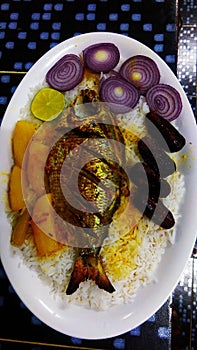 Fried fish vegetable starter white rice dates lemon and onions photo