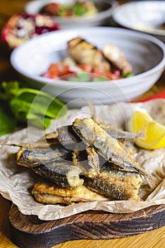 Fried fish on a wooden board on the table served with other dishes. Georgian cuisine concept