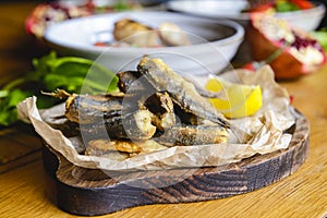 Fried fish on a wooden board on the table served with other dishes. Georgian cuisine concept