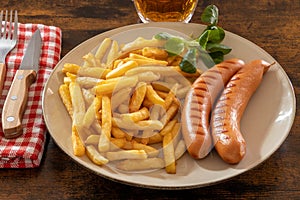 Fried with frankfurters in a plate on a table with a beer
