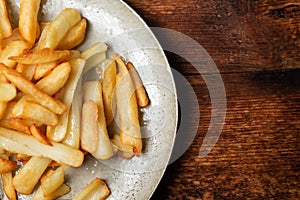 Fried French fries in wedges on a plate on a wooden background