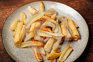 Fried French fries in wedges on a plate on a wooden background