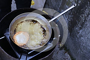 Fried fritter dipped in boiling oil in an aluminum pot