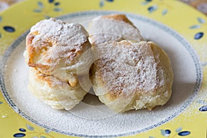 Fried fritters sifted by sugar powder on plate