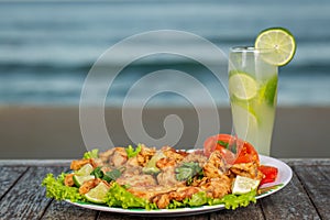 Fried frog legs with caipirinha cocktail with the beach in the background