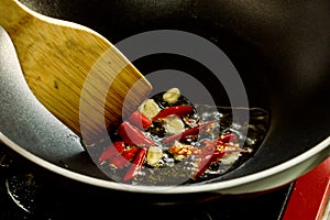 Fried garlic and red chilly in pan stir by wooden spoon