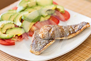 Fried Gilted Sea Beam with tomatoes and avocados. photo