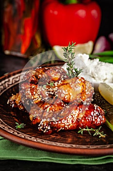 Fried glazed chicken wings in soy sauce and sesame. Cheese white sousa. Marinated vegetables on a ceramic plate. Background image