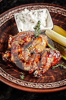 Fried glazed chicken wings in soy sauce and sesame. Cheese white sousa. Marinated vegetables on a ceramic plate. Background image