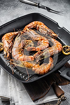 Fried on grill skillet Giant Black tiger prawns shrimps with lemon and herbs. Gray background. Top view