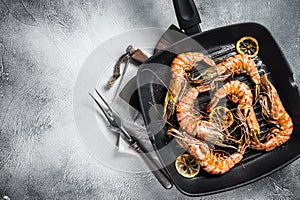 Fried on grill skillet Giant Black tiger prawns shrimps with lemon and herbs. Gray background. Top view. Free copy space