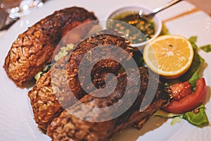 Fried grilled carp, roasted carp fish on plate with lemon and salad served in a traditional restaurant in Montenegro, Skadar lake