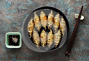 Fried Gyoza dumplings on a plate, soy sauce, chopsticks