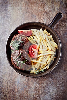 Fried hamburger steaks with tomatoes and french fries.