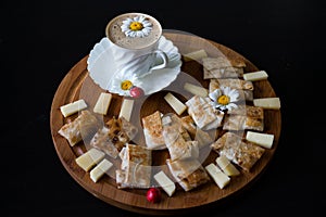 Fried homemade pies made of thin pita bread with homemade cheese and herbs, a white porcelain Cup and saucer with coffee, daisies