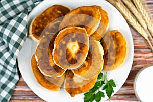 Fried homemade pies with meat and potatoes on a wooden table at the kitchen. Grandma`s recipe. Top view. Close-up