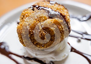 Fried ice cream with chocolate syrup and cream on plate