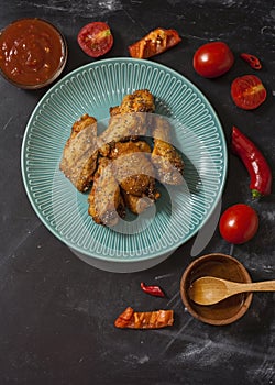 Fried juicy chicken wings marinated with honey, soy sauce, spices, sprinkled with chia seeds on a plate on a black