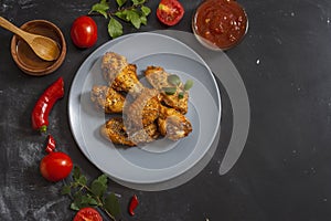 Fried juicy chicken wings marinated with honey, soy sauce, spices, sprinkled with chia seeds on a plate on a black