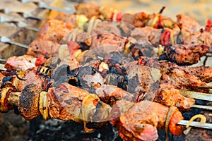 Fried and juicy meat is fried on skewers on a fire. Brazier from bricks. Charcoal and flame grill, picnic, holiday food.