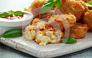 Fried Mac, macaroni and Cheese Bites in breadcrumbs with ketchup sauce on white wooden board
