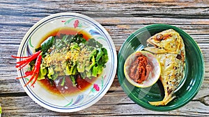 Fried mackerel served with Roasted chilli paste and kale fried in Oyster sauce on white plate , delicious menu for dinner.