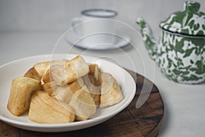 Fried marinated cassava on white plate with teapot and tea cup