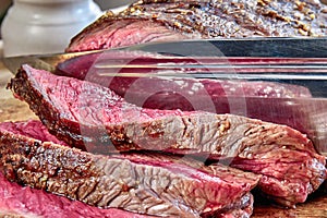 Fried meat with blood with hunting knife. Well done steak closeup. Rustic style.