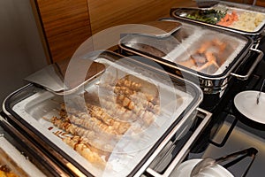 Fried meat on skewers and other appetizers in a food warmer on a buffet table in a hotel restaurant