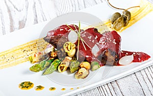 Fried meat steak with bbq sauce, asparagus and herbs on plate on wooden background. Hot Meat Dishes. Top view.