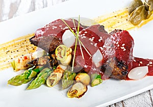 Fried meat steak with bbq sauce, asparagus and herbs on plate on wooden background. Hot Meat Dishes. Top view.