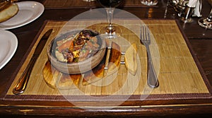 Fried meat and waxes on a dark frying pan on a wooden stand.