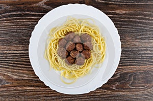 Fried meatballs with spaghetti in dish on dark wooden table. Top view