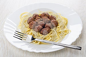 Fried meatballs with spaghetti, fork in dish on wooden table