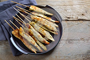 Fried mediterranean chicken skewers served as finger food snack for a festive party, rustic wooden table with copy space, high