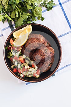 Fried minced meat kofta or kebabs served with vegetable saladf in a bowl. Close up. Middle eastern food concept