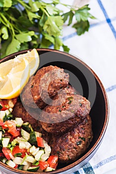 Fried minced meat kofta or kebabs served with vegetable saladf in a bowl. Close up. Middle eastern food concept