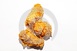 Fried mouth-watering three chicken wings in a spicy sauce and brown breaded lie in a handful isolated on a white background,