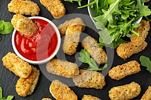 Fried mozzarella cheese sticks in breadcrumbs with ketchup sauce and wild rocket leaves