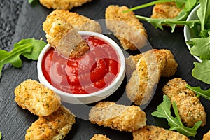 Fried mozzarella cheese sticks in breadcrumbs with ketchup sauce and wild rocket leaves