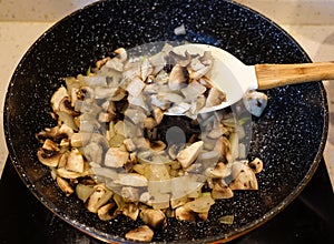Fried mushrooms in the pan. Spoon for mixing mushrooms