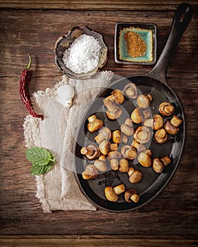 fried mushrooms with salt and pepper on a wooden background