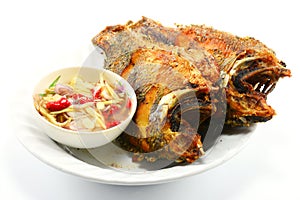 Fried nile tilapia fish with mango sauce on white plate on white background