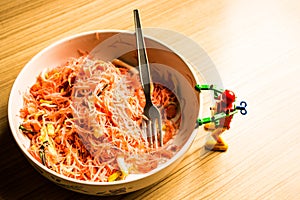 Fried noodle in a bowl of pink and a small robot.