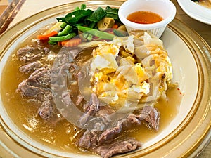 Fried noodle mixed with egg in beef gravy sauce serving on plate